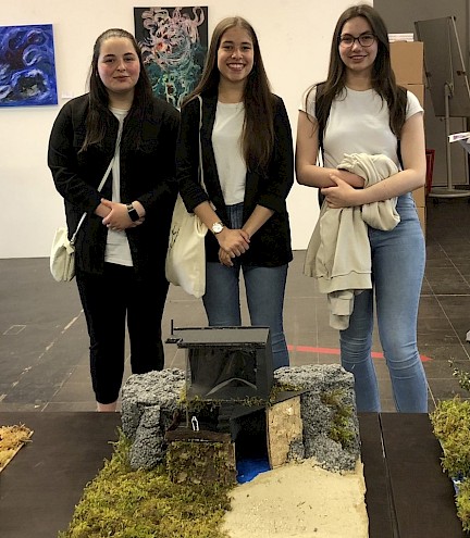 Drei Schülerinnen, die beim Siegermodell des Schülerwettbewerbs im Architekturmodellbau stehen